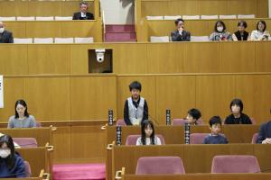 こども議会体験会でこども（2人目）が議員席で質問している様子の写真