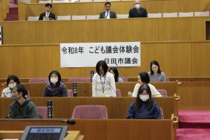 こども議会体験会でこども（6人目）が議員席で質問している様子の写真